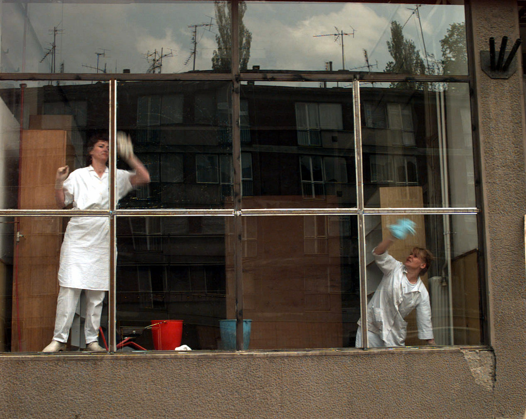 Two women concentrate on cleaning the windows.